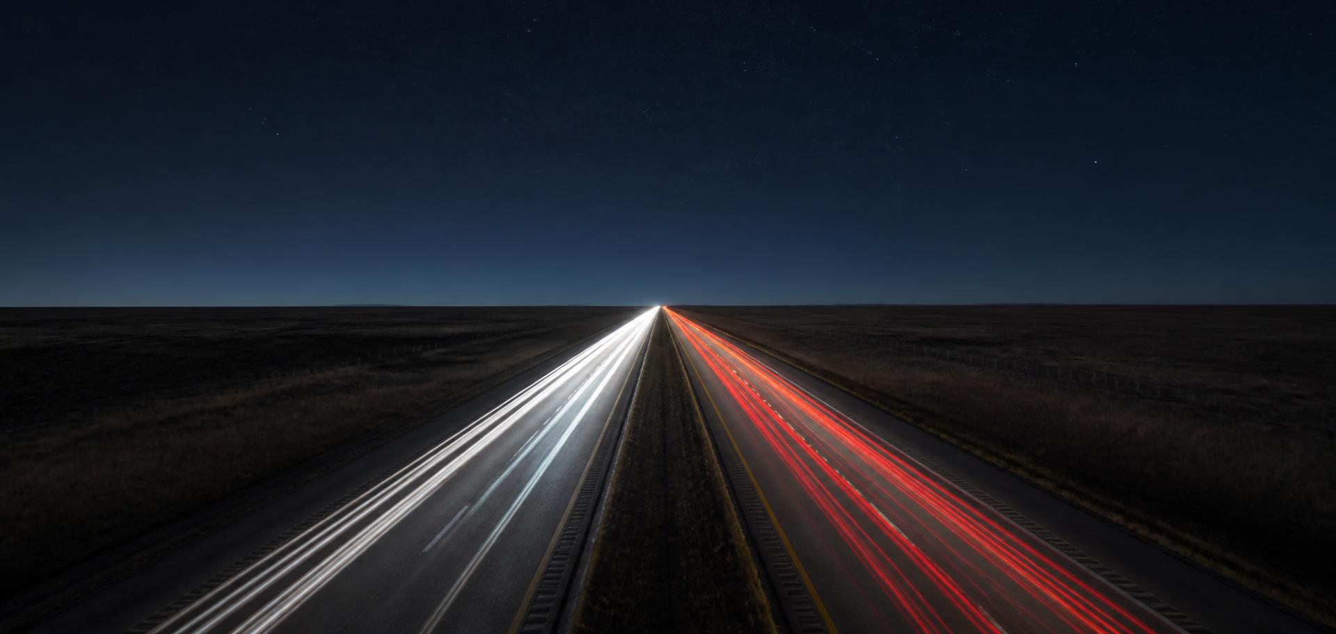 Trucks on a highway at night with light trails